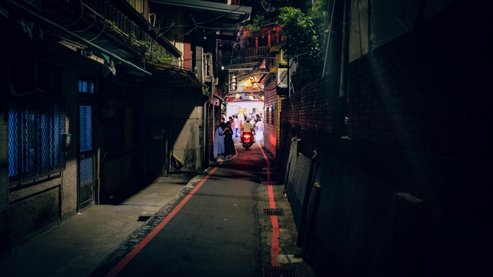 九份の夜の路地で赤い灯りとスクーターが見える古い町並み