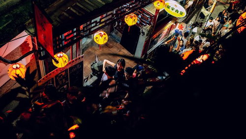 夜間営業する九份の細い路地と黄色い提灯の風景