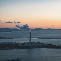 コスモタワーの展望台から見た夕焼けと発電所の煙の写真