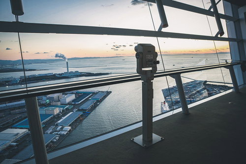 大阪府咲洲庁舎展望台内の双眼鏡と夕暮れ時の湾景