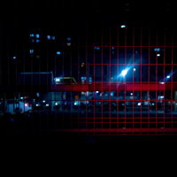 赤色ライトが反射する暗いメッシュフェンスの写真