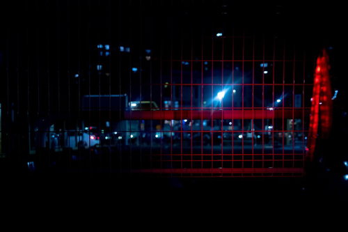 赤色ライトが反射する暗いメッシュフェンス