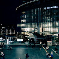 ライトアップされたグランドフロント大阪前を行き交う人々の写真