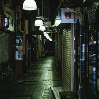 閉店後のシャッターが並ぶ薄暗い路地の夜間風景の写真