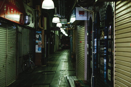 閉店後のシャッターが並ぶ薄暗い路地の夜間風景