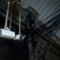 建物の壁に設置された白い防犯カメラが周囲を監視の写真