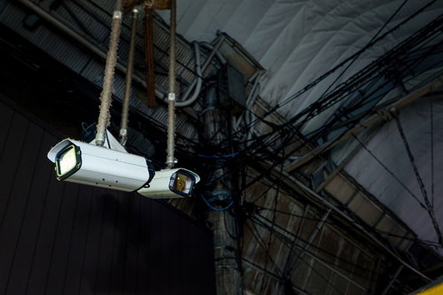 建物の壁に設置された白い防犯カメラが周囲を監視