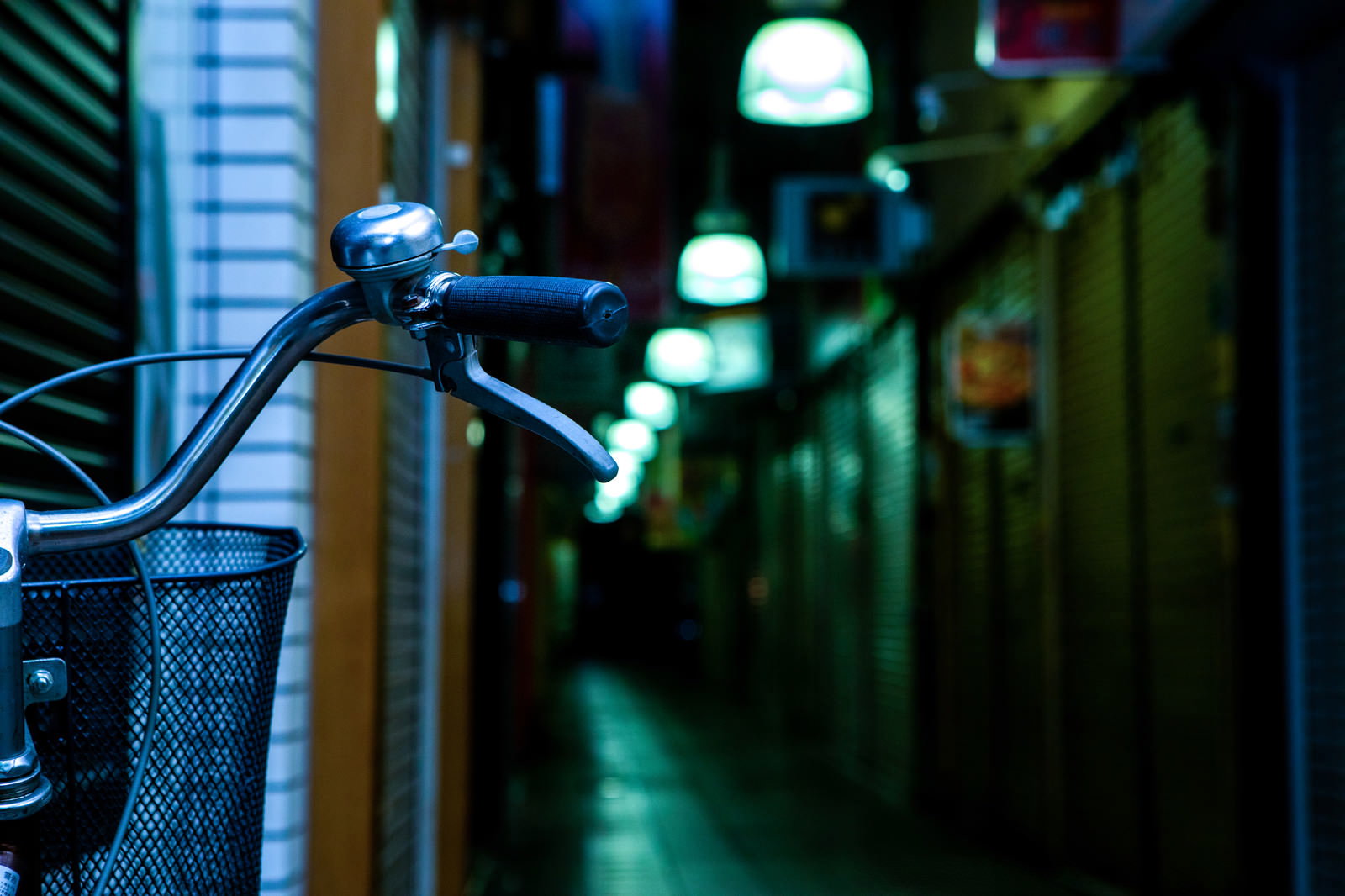 夜の薄暗い路地裏に停められた自転車のハンドル部分