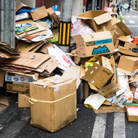 道路脇に積み重ねられたダンボール箱のゴミ山の写真