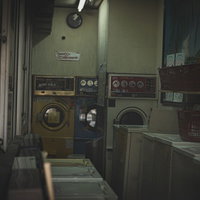 薄暗い蛍光灯の下に古い洗濯機が並ぶコインランドリーの写真