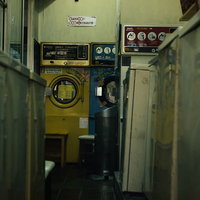 薄暗いコインランドリーに並ぶ昭和レトロな洗濯機の写真