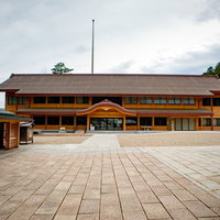 出雲大社の祈祷受付所の木造建築と境内の参拝風景の写真