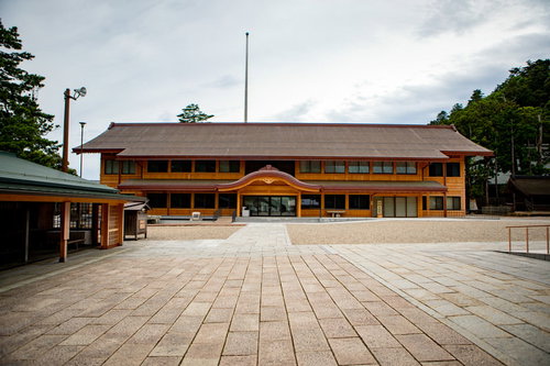 出雲大社の祈祷受付所の木造建築と境内の参拝風景