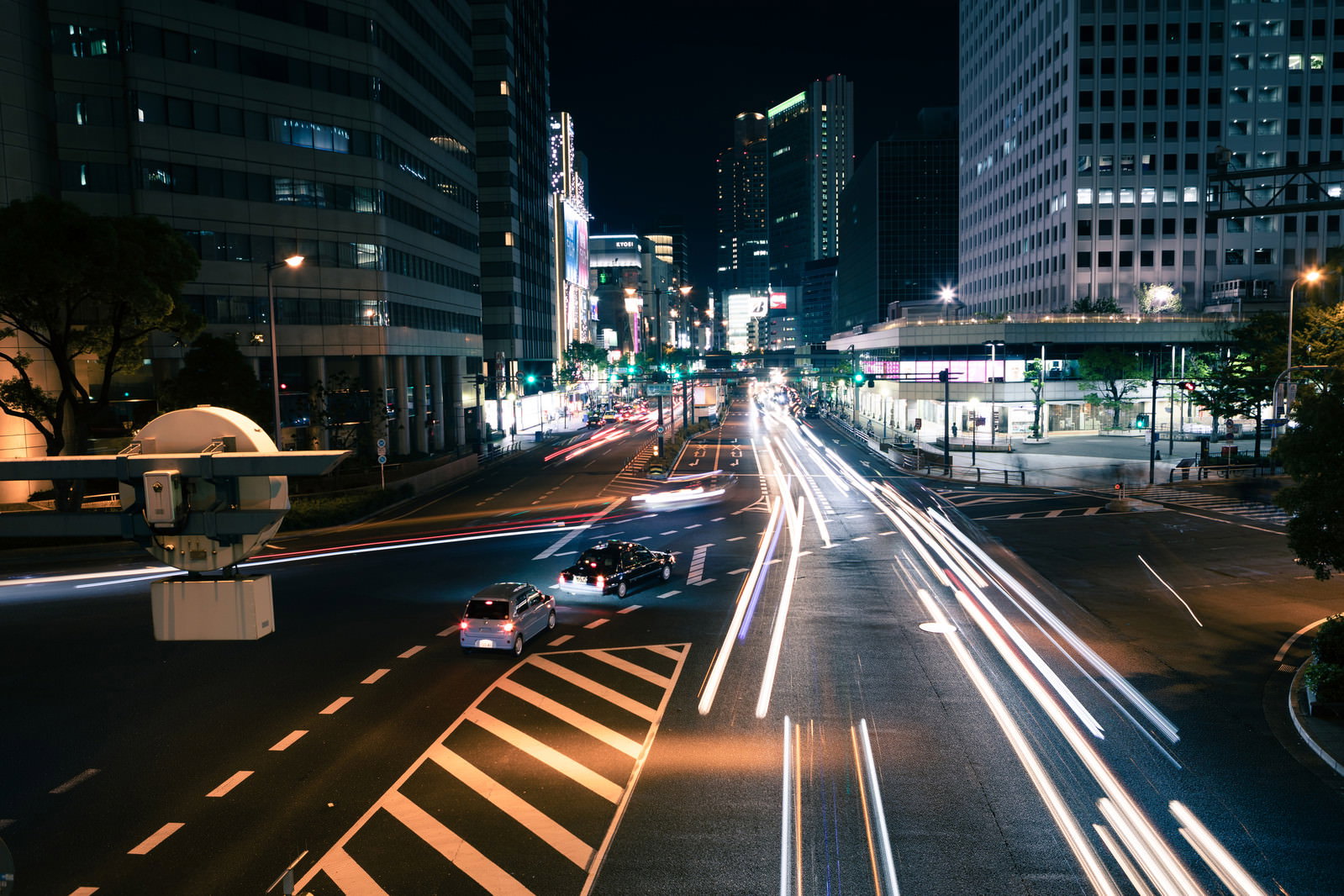 夜の交差点で車のライトが光跡を描く都市の夜景