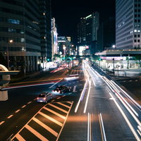 夜の交差点を行き交う車のライトが描く光跡の写真