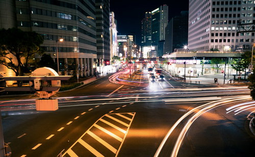 夜の交差点を行き交う車のヘッドライトとテールライトの光跡