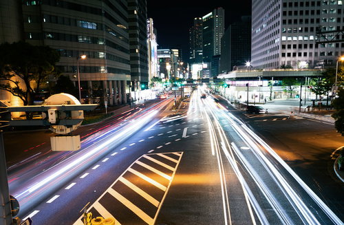 夜間の道路を直進する車の光跡と交差点の信号