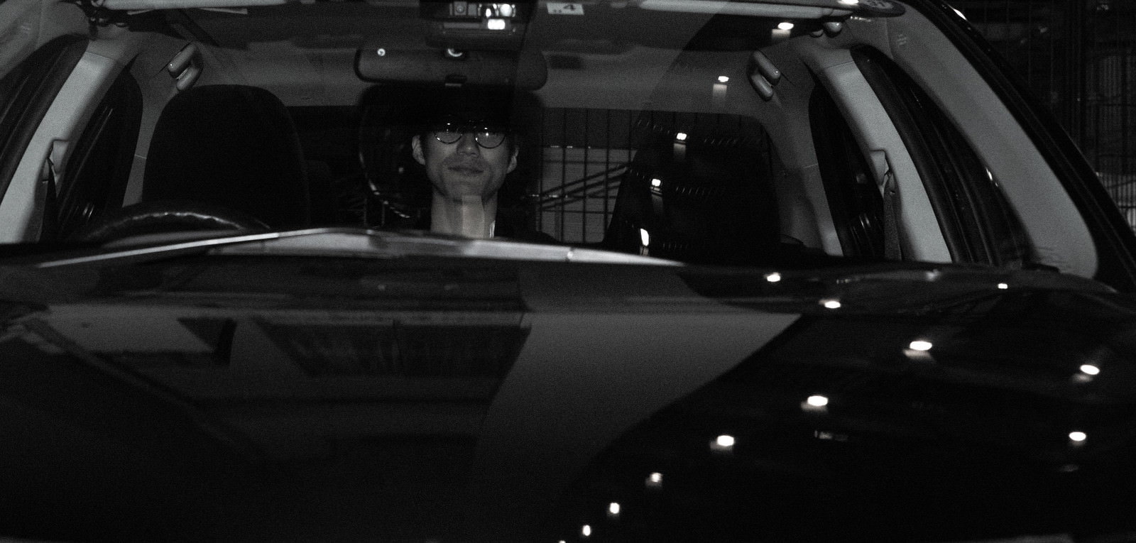 車の後部座席に身を潜めて隠れている人のシルエット［モデル：村田裕章］