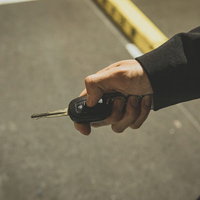 スマートキーで車のロック解錠を操作するビジネスマンの写真