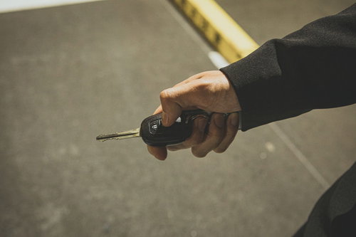 スマートキーで車のロック解錠を操作するビジネスマン