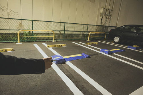 夜の駐車場で車を解錠する男性