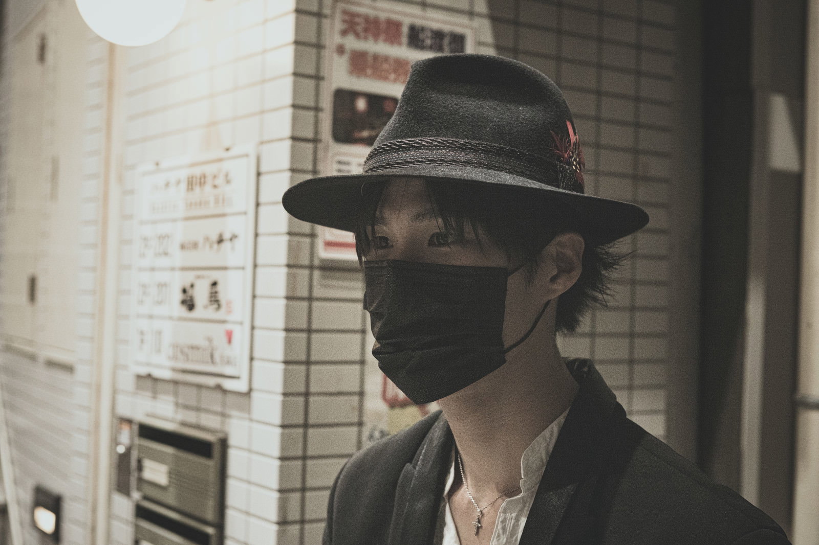 黒マスクと黒い帽子を着用して駅のホームを歩く出勤中の男性［モデル：村田裕章］