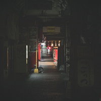 店が閉まる深夜の飲み屋の路地裏で小瓶を持つ手の写真