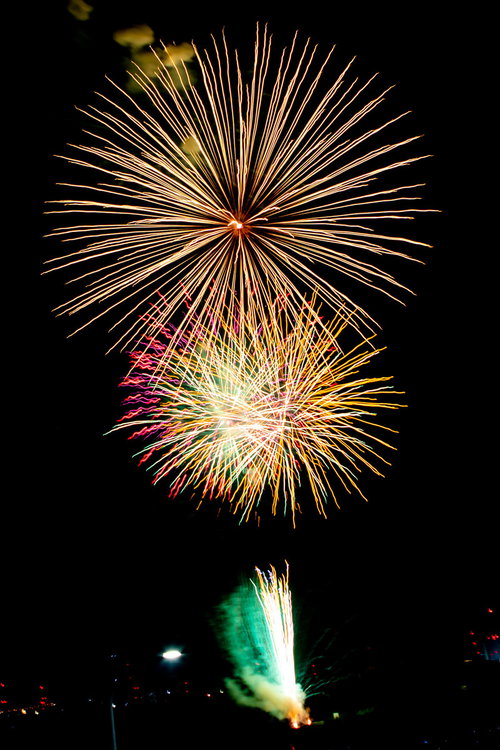 ドドンと打ち上がるオレンジ色の大輪花火が夜空で炸裂する打上花火の瞬間