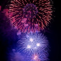 夜空を彩る大小の打ち上げ花火が炸裂する瞬間の写真