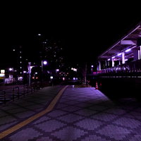 誰もいない深夜の駅前の歩道を照らす街灯の夜景の写真
