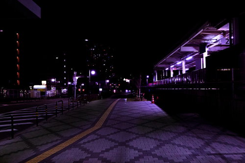 誰もいない深夜の駅前の歩道を照らす街灯の夜景