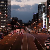 赤信号で止まる車と街並みの夕暮れ時の都市風景の写真