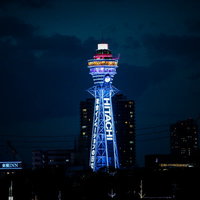 青いネオンでライトアップされた夜の通天閣の写真