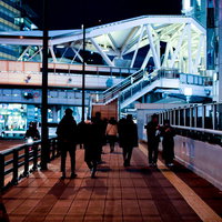 夜の歩道橋を行き交う人のシルエットの写真