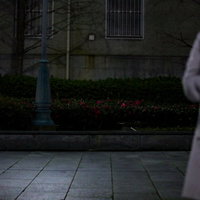 待ち合わせには向かない薄暗い歩道の花壇前に立つ人影の写真