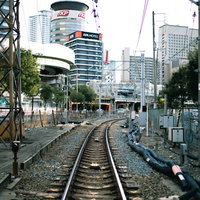 高層ビルが立ち並ぶ市街地へと向かう線路と鉄道レールの写真