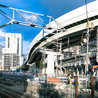 青空の下で進む鉄道高架橋と工事現場の建設風景の写真