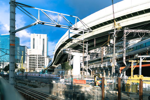 青空の下で進む鉄道高架橋と工事現場の建設風景