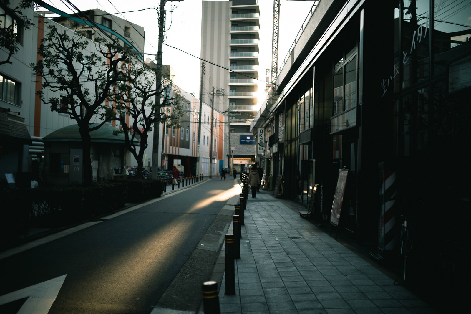 夕日の光が差し込む路地裏の歩道に並ぶ建物と店舗