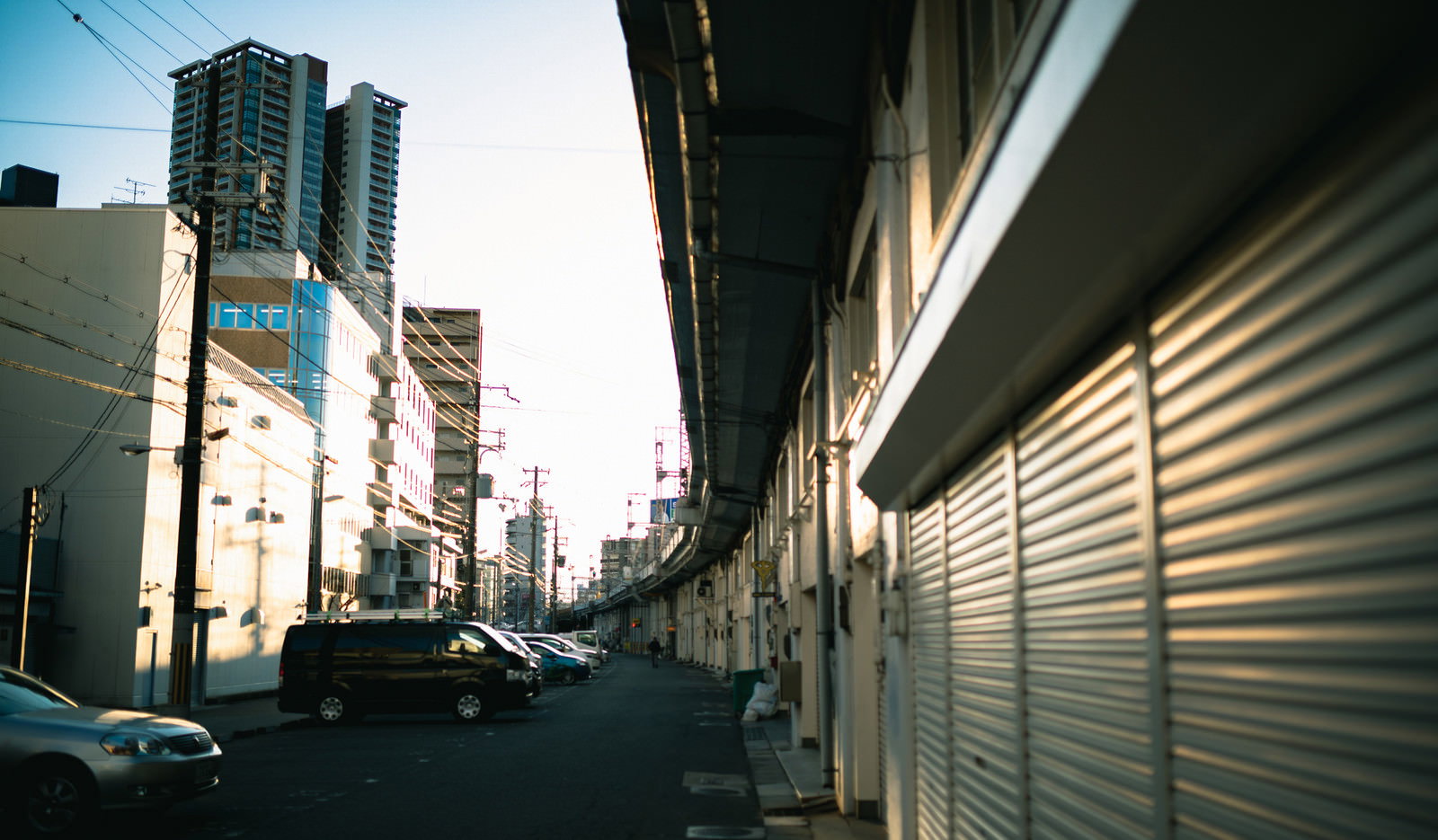 高架橋の下にある駐車場と建物のシャッターが連なる都市の街並み