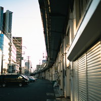 高架橋沿いの駐車場スペースとシャッター付き建物の都市風景の写真