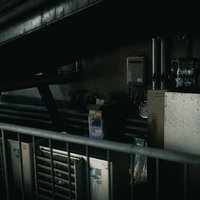 薄汚れた不用品置き場に置かれた室外機と古い設備の写真