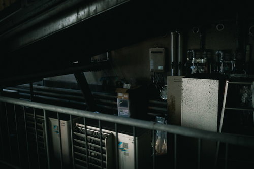 薄汚れた不用品置き場に置かれた室外機と古い設備