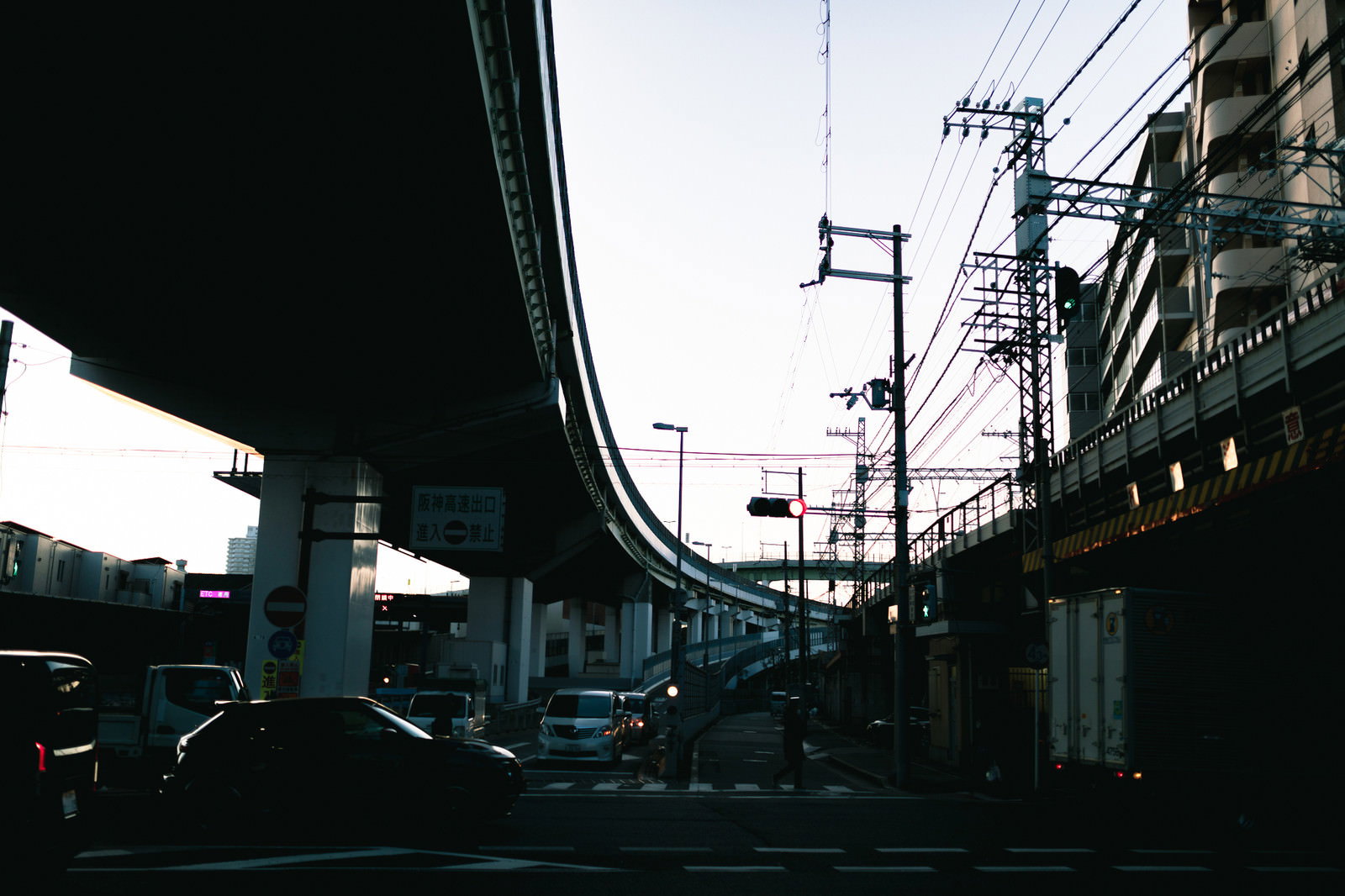 曇り空の下の高速道路出口と高架橋、道路標識と電線が見える都市インフラ