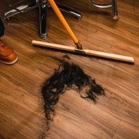 ヘアカット後に床屋の床に散らばった黒い髪の毛の写真