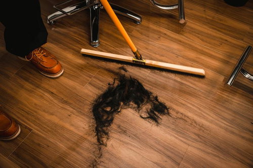 ヘアカット後に床屋の床に散らばった黒い髪の毛