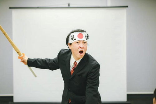 白いはちまきで竹刀を握り気合を入れるスーツの男性