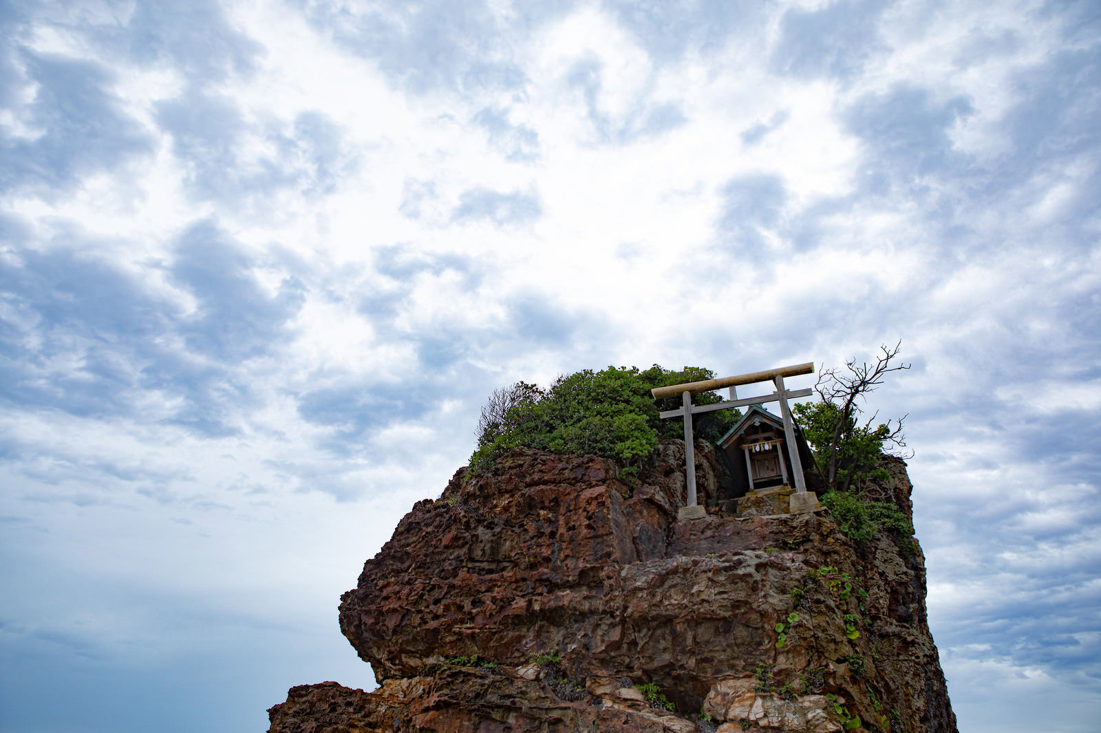 稲佐の浜の弁天島に立つ白い鳥居と岩場の風景