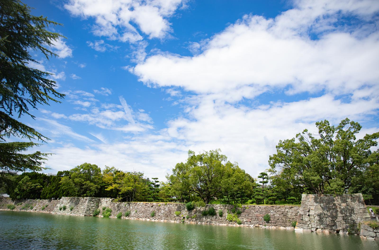 広島城の水堀に面した石垣と緑の木々、青い空