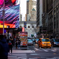 ニューヨークの高層ビル街で人々が行き交う横断歩道と街並みの写真